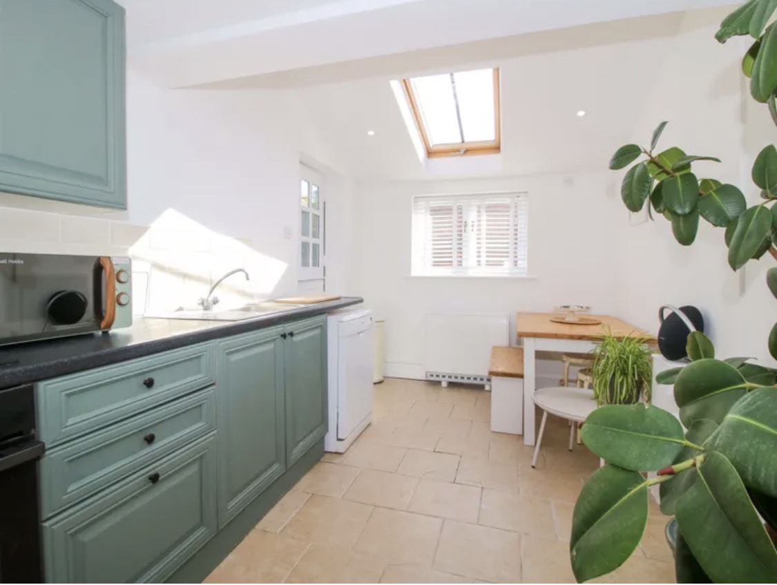 Green kitchen cabinets, dining nook and skylight